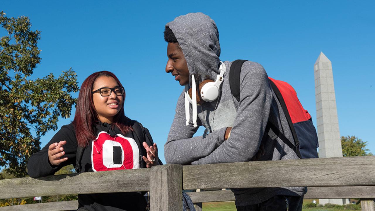 Two Ohio State students talking by the fence in the grove.